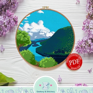 May include: A cross stitch pattern of a river winding through a green valley with a blue sky and white clouds. The pattern is in a round embroidery hoop and a red circle with the text "Cross Stitch Pattern PDF Download" is in the lower right corner.