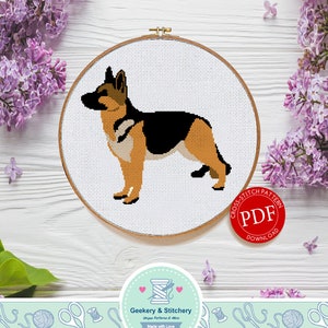 May include: A cross-stitch pattern PDF download for a German Shepherd dog. The pattern is displayed in a white embroidery hoop with a brown wooden frame. The image also includes a red circle with the text "Cross Stitch Pattern PDF Download" in white.