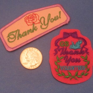 May include: Two embroidered patches with "Thank You" text. One is peach with a rose and green text, the other is red with a dove, bow, and "Thank You Volunteer" text. A quarter is next to the patches.
