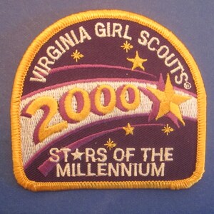 May include: Purple and gold embroidered patch with the text "Virginia Girl Scouts" and "2000 Stars of the Millennium".