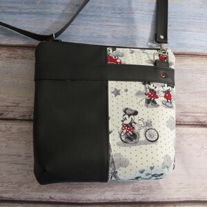 Puede incluir: Bolso bandolera de Mickey Mouse y Minnie Mouse en blanco y negro con una solapa de piel sint&eacute;tica negra. El bolso tiene un fondo blanco con lunares negros y estrellas.