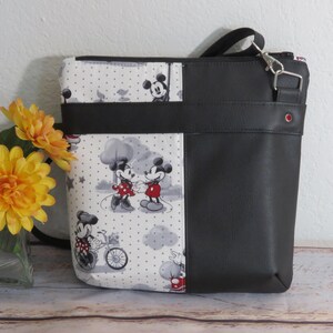 Puede incluir: Bolso de tela con estampado de Mickey Mouse y Minnie Mouse en blanco y negro con solapa y correa de piel sint&eacute;tica negra. El bolso tiene cierre de cremallera y un peque&ntilde;o bolsillo en la parte delantera.