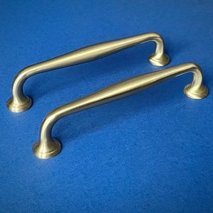 May include: Two silver cabinet door pulls with a curved design.