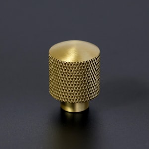 Peut inclure: Un bouton de porte en laiton doré avec un motif texturé en forme de diamant.