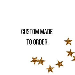 Pu&ograve; includere: Uno sfondo bianco con il testo nero CUSTOM MADE TO ORDER. centrato. Diverse stelle a cinque punte con una finitura glitterata dorata testurizzata sono disposte in modo sparso sul lato inferiore destro dell'immagine.