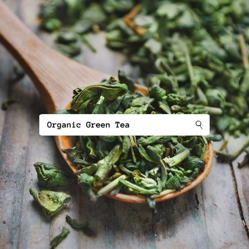 May include: A wooden spoon filled with loose green tea leaves. The text "Organic Green Tea" is displayed above the spoon.