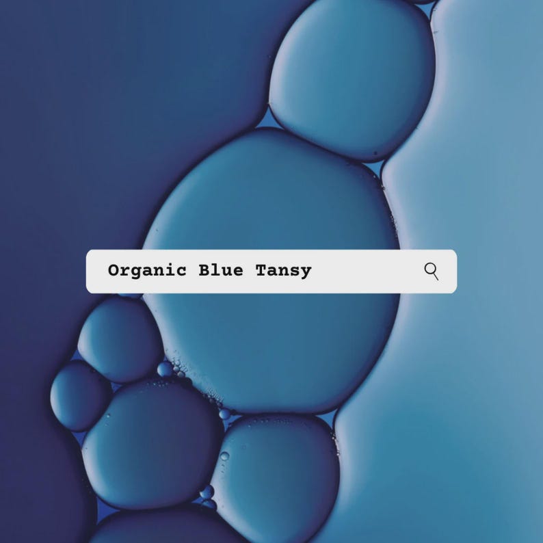 K&ouml;nnte beinhalten: Eine wei&szlig;e rechteckige Suchleiste mit dem Text Organic Blue Tansy und einem Lupensymbol, &uuml;berlagert auf einem Hintergrund aus abstrakten, sich &uuml;berlappenden kreisf&ouml;rmigen blauen und dunkelindigo-farbenen Fl&uuml;ssigkeitstropfen.