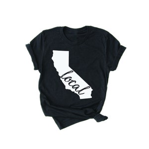 May include: A black t-shirt with a white outline of the state of California and the word "local" written inside the outline.