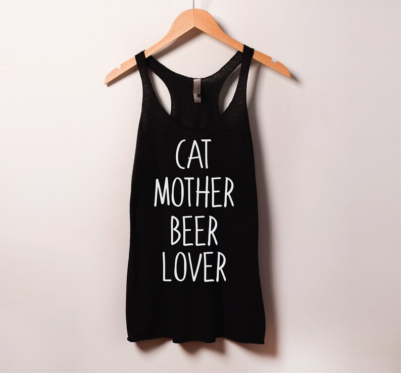 Może przedstawiać: Czarny top na ramiączkach z białym napisem "Cat Mother Beer Lover".