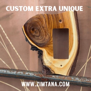 May include: A custom, extra unique wooden light switch cover. The cover is made from a single piece of wood with a natural edge, featuring a rectangular cutout for the switch and two screw holes. The text "CUSTOM EXTRA UNIQUE" and "WWW.ZIMTANA.COM" are visible.