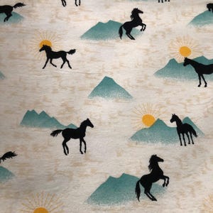 May include: Off-white fabric with a repeating pattern of black horse silhouettes, teal mountains, and yellow suns. The design evokes a sense of the American West and the outdoors.