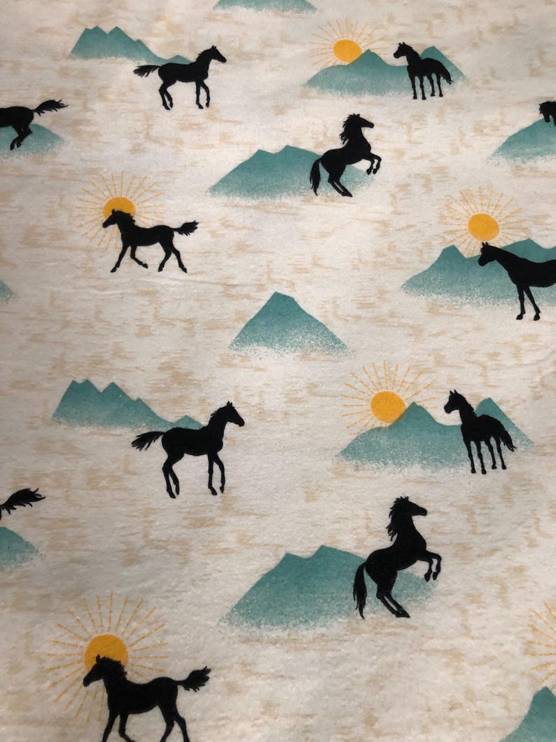 May include: Off-white fabric with a repeating pattern of black horse silhouettes, teal mountains, and yellow suns. The design evokes a sense of the American West and the outdoors.
