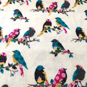 May include: A white fabric with a repeating pattern of colorful birds. The birds are black, blue, yellow, pink, and green. The birds are perched on branches with green leaves.