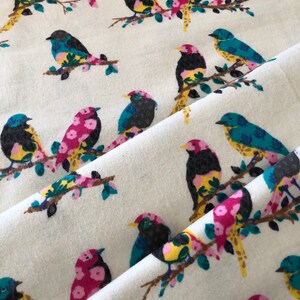 May include: White fabric with a repeating pattern of colorful birds perched on branches. The birds are a mix of pink, yellow, blue, and black.