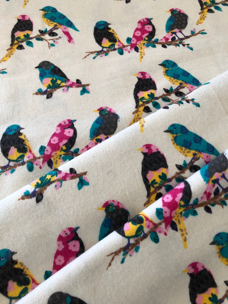 May include: White fabric with a repeating pattern of colorful birds perched on branches. The birds are a mix of pink, yellow, blue, and black.