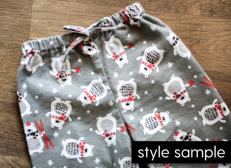Puede incluir: Pantalones de pijama grises con un estampado repetido de osos polares blancos con bufandas rojas y bastones de esqu&iacute; rojos. Los pantalones tienen una cintura con cord&oacute;n y las palabras "style sample" est&aacute;n impresas en la parte inferior derecha.