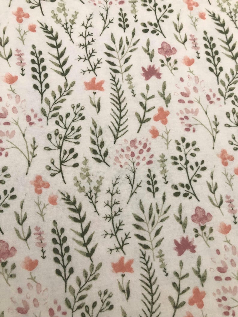 Puede incluir: Una tela con un patr&oacute;n floral repetido. El dise&ntilde;o presenta varios elementos bot&aacute;nicos verdes, rosas y melocot&oacute;n, incluyendo hojas y flores, sobre un fondo blanco. El patr&oacute;n es delicado y detallado.