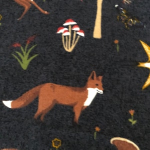 Pode incluir: Um tecido azul escuro com um padr&atilde;o repetido de uma raposa, um veado, cogumelos e &aacute;rvores. O padr&atilde;o &eacute; em tons de marrom, vermelho, branco e amarelo.