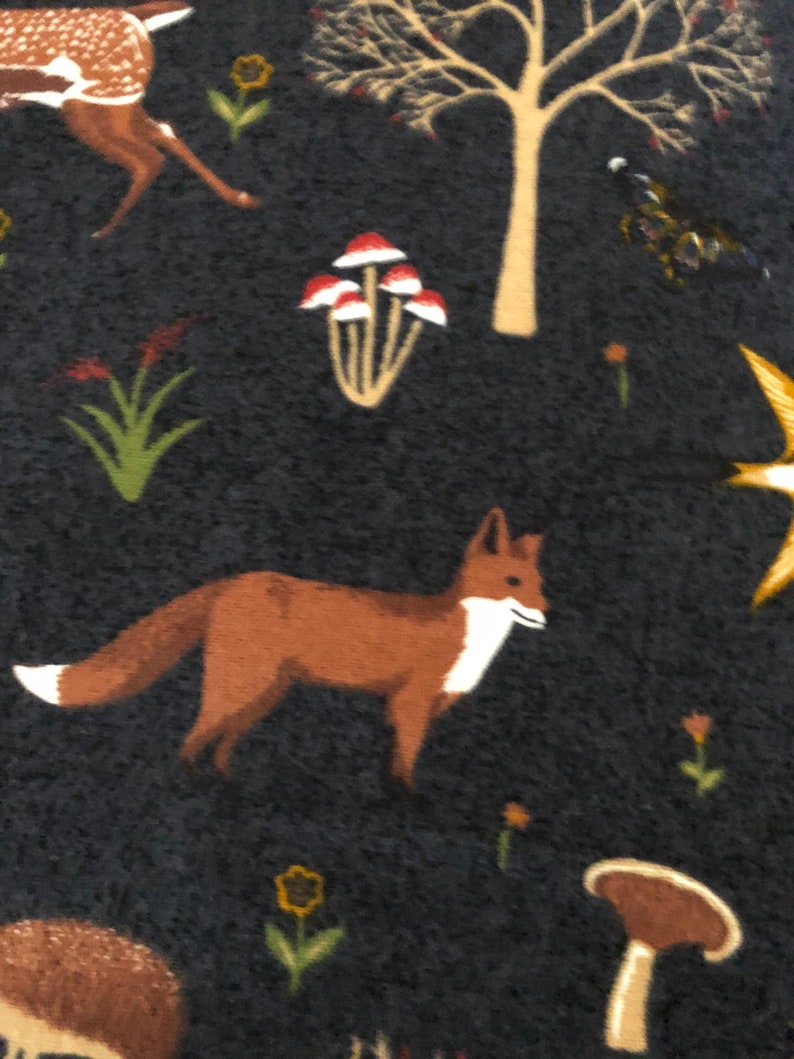 Pode incluir: Um tecido azul escuro com um padr&atilde;o repetido de uma raposa, um veado, cogumelos e &aacute;rvores. O padr&atilde;o &eacute; em tons de marrom, vermelho, branco e amarelo.