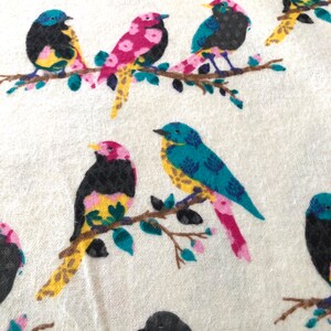 May include: A white fabric with a repeating pattern of colorful birds perched on branches. The birds are pink, blue, yellow, and black with intricate details.
