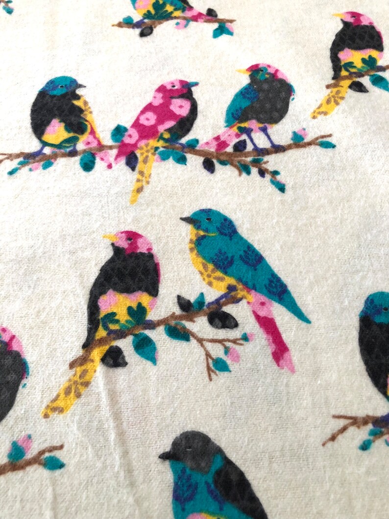 May include: A white fabric with a repeating pattern of colorful birds perched on branches. The birds are pink, blue, yellow, and black with intricate details.