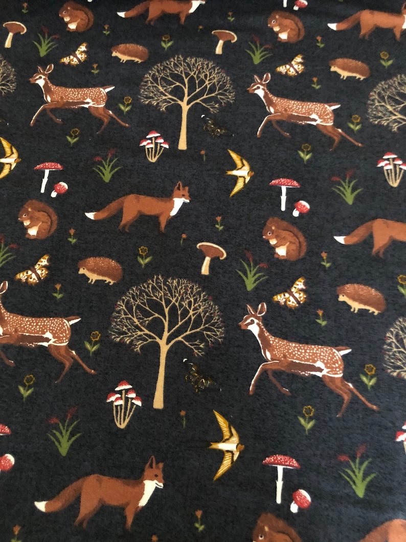 Pode incluir: Um tecido azul escuro com um padr&atilde;o repetitivo de animais da floresta, incluindo raposas, veados, esquilos e ouri&ccedil;os. O padr&atilde;o tamb&eacute;m inclui cogumelos, &aacute;rvores e p&aacute;ssaros.