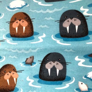 Może przedstawiać: Niebieskie tło z powtarzającym się wzorem mors&oacute;w i ryb. Morsy są brązowe, szare i czarne i mają białe kły. Ryby są białe i szare.