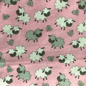 May include: Pink fabric with a repeating pattern of white sheep with gray polka dots and gray faces, interspersed with small gray birds. The sheep have a fluffy appearance, and the birds have simple, stylized designs.