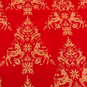 May include: Red fabric with a repeating pattern of gold reindeer and snowflake designs. The reindeer are stylized and arranged in a Christmas tree formation, creating a festive holiday theme.