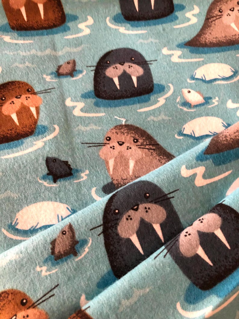 Może przedstawiać: Niebieski materiał z powtarzającym się wzorem brązowych, szarych i czarnych morsa z białymi kłami. Morsy pływają w niebieskiej wodzie z białymi falami i kry.