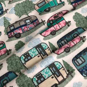 May include: White fabric with a repeating pattern of vintage camper trailers in teal, pink, and blue, adorned with floral and geometric designs. The design includes green trees and blue clouds, creating a whimsical, outdoorsy theme.