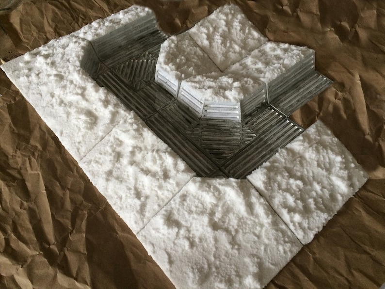 May include: A white, textured, foam-like material is used to create a model of a snowy landscape. The material is arranged in a series of squares and rectangles, with a raised, textured surface that resembles snow.