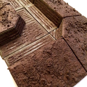 Pode incluir: Uma pe&ccedil;a de terreno modular texturizada de cor marrom para jogos de mesa. A pe&ccedil;a &eacute; projetada para representar uma trincheira com uma superf&iacute;cie de terra texturizada e um piso de metal verde.