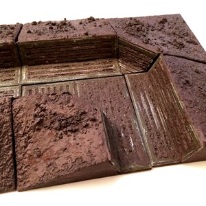 Pode incluir: Um conjunto de azulejos de pl&aacute;stico texturizados marrons e verdes que podem ser usados para criar uma trincheira para um jogo de guerra ou um jogo de miniaturas.