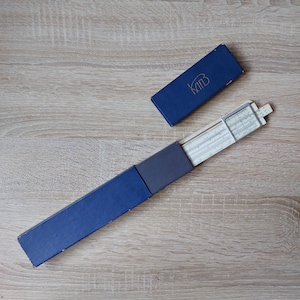 May include: A blue slide rule in a blue case with the word "K&E" printed on the case.