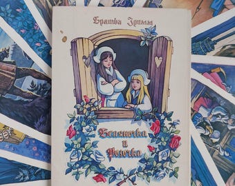 May include: A vintage book cover featuring an illustration of two girls in a window, surrounded by roses. The title at the top reads "Братья Гримм" and the title at the bottom reads "Беляночка и Розочка". The cover has a cream background.