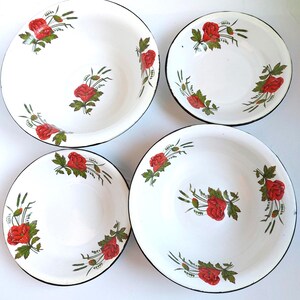 Peut inclure: Quatre bols et assiettes en émail blanc avec un motif de roses rouges et de feuilles vertes. Les bords sont noirs. Les bols et les assiettes sont disposés en carré.
