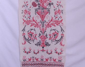 Peut inclure: Textile crème brodé au point de croix. Le motif présente un arrangement floral central rouge et noir, avec des oiseaux stylisés et des bordures décoratives. Une pièce vintage et artisanale.