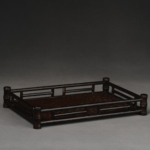 Puede incluir: Una bandeja rectangular de bamb&uacute; marr&oacute;n oscuro con un fondo tejido y un borde elevado. La bandeja est&aacute; hecha de bamb&uacute; natural y tiene un aspecto r&uacute;stico y artesanal.