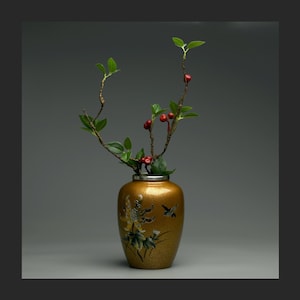 Peut inclure: Un vase doré avec un motif floral et une petite branche avec des baies rouges.