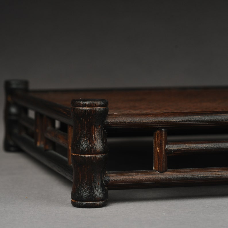 Op de afbeelding: Een donkerbruine houten displaystandaard met een vierkante bovenkant en een decoratief tralieontwerp. De standaard is gemaakt van dik, stevig hout en heeft een rustieke, antieke uitstraling.