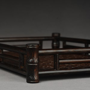 Puede incluir: Una bandeja rectangular de color marr&oacute;n oscuro hecha de bamb&uacute; tejido con un borde elevado. La bandeja tiene un acabado de madera natural y es perfecta para servir aperitivos o bebidas.