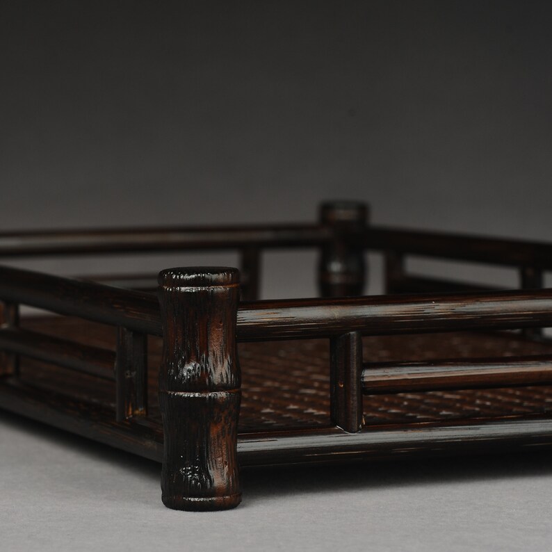 Puede incluir: Una bandeja rectangular de color marr&oacute;n oscuro hecha de bamb&uacute; tejido con un borde elevado. La bandeja tiene un acabado de madera natural y es perfecta para servir aperitivos o bebidas.