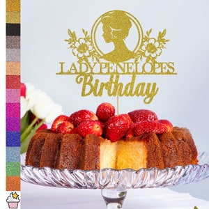 May include: Gold glitter cake topper with a silhouette of a woman's head and the text "Lady Penelope's Birthday".