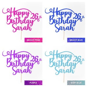 May include: Four cake toppers with the text "Happy 26th Birthday Sarah" in different glitter colors: bright pink, bright blue, purple, and baby blue.