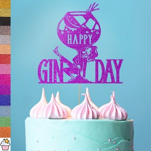 Op de afbeelding: Paarse glittertaarttopper met een vrouw die tegen een gin-glas leunt en de tekst "Happy Gin Day".