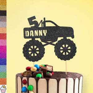 Può includere: Topper per torta di camion mostro in glitter nero con il numero 5 e il nome Danny. Il topper è su una torta al cioccolato con caramelle colorate.