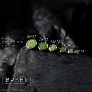 May include: Five round stud earrings with green textured centers and metallic bezels, arranged by size from 8mm to 4mm. Text indicates posts are stainless steel or titanium and bezels are stainless steel. The brand name :BURHL is visible.