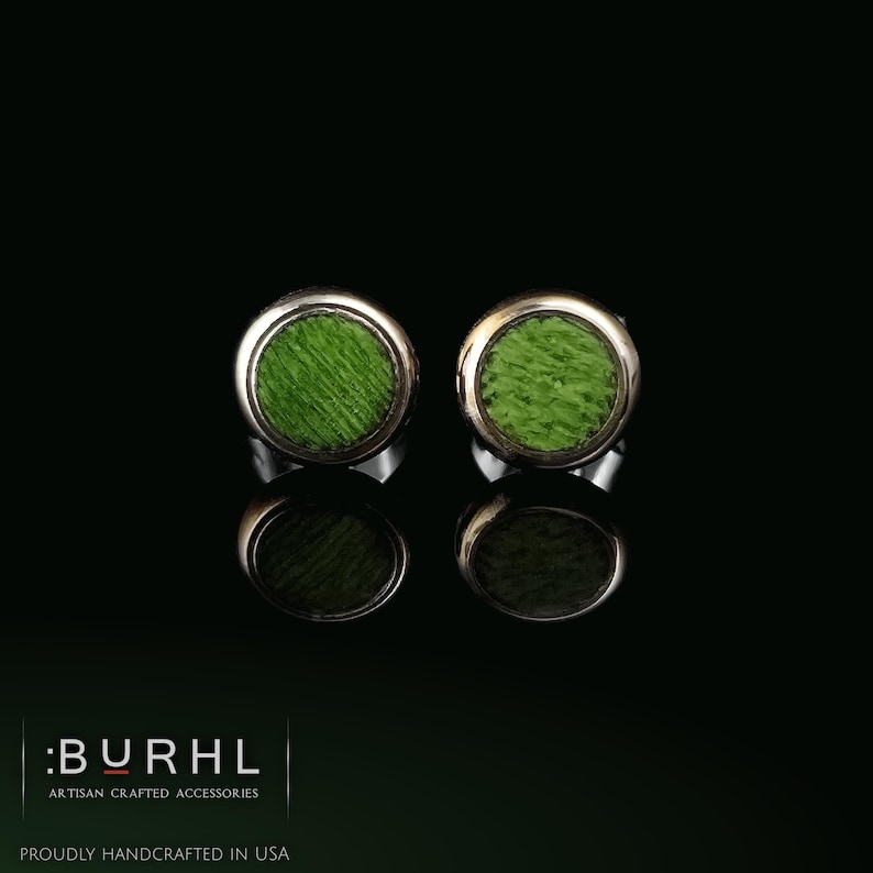 May include: A pair of circular stud earrings featuring a bright green textured center inlay surrounded by a polished silver-tone metal rim. The text :BURHL ARTISAN CRAFTED ACCESSORIES PROUDLY HANDCRAFTED IN USA is visible in the bottom left corner.