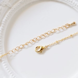 May include: A gold chain necklace with a lobster clasp closure. The chain is made of small, round links.